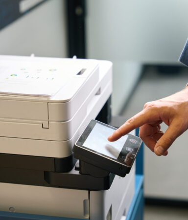Employee uses office equipment to work with documents, he is in comfortable casual clothes